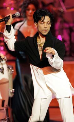 prince performing on stage at an event with his hands in the air while holding a microphone