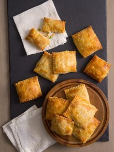 several small pastries on a wooden plate next to napkins and white paper towels