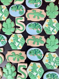 cookies decorated with green and blue icing are arranged in the shape of letters, numbers, and lizards