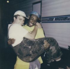 two young men hugging each other in front of a trailer