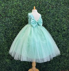 Our enchanting Ankle Length flower girl dresses are sure to turn heads! Bodice is made of Mint satin, waist consists of a matching sowed in sash (NOT DETACHABLE) The back of the dress has an open deep V-Back with a hidden zipper, followed by a detachable bow. The skirt has 4 Mint tulle layers for fullness, the top layer of tulle is ivory with ivory pearls. The dress has 2 layers of lining with crinoline. This dress is perfect for any occasion!  Dress Is Pictured with a petticoat NOT INCLUDED htt Spring Wedding Ball Gown Pageant Dress, Spring First Communion Tulle Gown, Spring Princess First Communion Dress For Pageant, Spring Princess Style First Communion Dress For Pageant, Green Princess Dress For Bridesmaids, Princess Style First Communion Dress For Spring Pageant, Green Princess Dress With Bow, Spring Tulle Ball Gown For First Communion, Spring Princess Style First Communion Tulle Dress