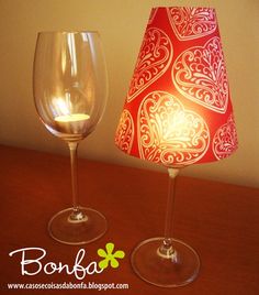 two wine glasses sitting on top of a table next to a red and white lamp