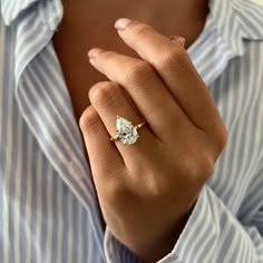 a woman wearing a ring with a pear shaped diamond