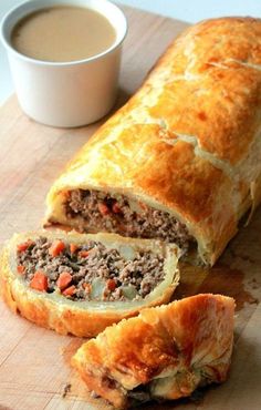 a meat filled pastry cut in half on a cutting board