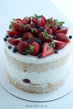 there is a cake with strawberries on it and flowers around the edges, along with greenery