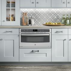 an image of a kitchen setting with white cupboards and gray stove top oven in the center