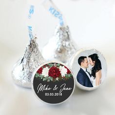 a couple kissing in front of some silver foil wrapped herspoos with red and white flowers on them