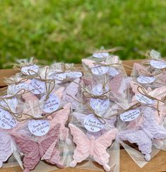 some pink and white butterflies are sitting on top of clear bags with tags attached to them