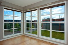 an empty room with large windows and wood flooring on the outside, looking out onto a city