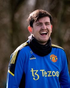 a young man laughing while wearing a blue shirt