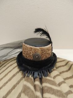 "Woman's Top Hat, Top Hat with Veil, Bolero Top Hat, Southwest Top Hat, Hat, Leather Top Hat, Satin Top Hat, Fringe Top Hat. This top hat has a southwestern flare, with the top and the brim covered in black leather and the side covered with gold crinkled satin. A gold and black cameo, and a 8\" black ostrich feather, 1 1/2\"concho style button on the front and two on the sides of the black leather hat band. The back is adorned with a black tulle gathered veil that is approx. 20\" in length. The Top Hat With Veil, Black Leather Hat, Leather Top Hat, Hat With Veil, Black Cameo, Veiled Woman, Bolero Top, Leather Hat, Top Hats