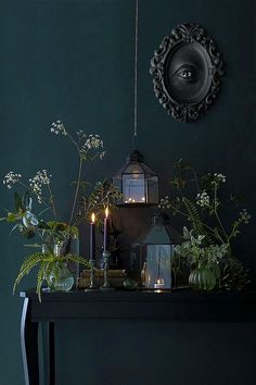 a table topped with plants and candles next to a mirror