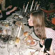 a group of people sitting at a table with food and drinks in front of them