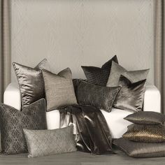 a bunch of pillows sitting on top of a white couch in front of a wall