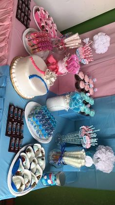 a table topped with cakes and cupcakes on top of a blue table cloth