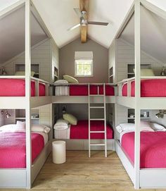 bunk beds are lined up in an attic dormer with pink bedding and pillows