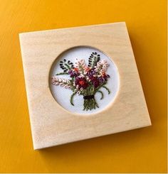 a wooden frame with flowers in it on a yellow tableclothed surface is shown