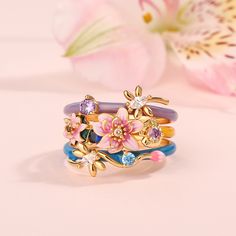 There is nothing more collectible than this precious stacking ring. Transforming the iconic "Water Lilies" from Monet into an unexpected and artistic treasure, this beautifully detailed stacking ring boasts charming lotuses in bright shades of enamel and dragonflies. In Monet's painting of the water lilies, dragonflies are not visible. The dragonfly is the designer's imagination of Monet's water lily pond. This stacking ring showcases the dreamlike play of light and shadow on the shimmering wate Flower Shaped Stackable Promise Rings, Stackable Flower Promise Rings, Fine Jewelry Stackable Flower Ring For Anniversary, Stackable Open Flower Ring For Anniversary, Anniversary Stackable Flower Ring In Fine Jewelry Style, Anniversary Stackable Fine Jewelry Flower Ring, Anniversary Flower Ring With Stackable Open Design, Anniversary Flower Ring Open And Stackable, Gift Stackable Enamel Open Ring