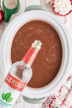 a bottle of leroux is sitting in front of a bowl of chocolate and marshmallows