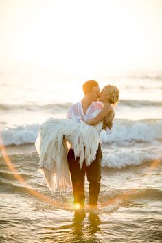 a man holding a woman while standing in the ocean