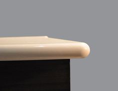 a close up view of a white toilet seat on a black countertop against a gray background