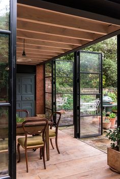 an enclosed patio with table, chairs and potted plants