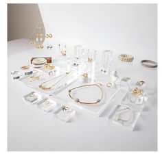 an assortment of jewelry is displayed on a white surface with gold rings and bracelets