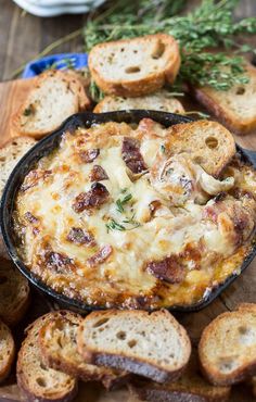 a dish with bread and cheese on a wooden table next to some garlic bread slices