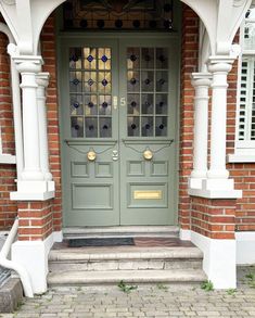 the front door to a brick building with two white pillars and windows on each side