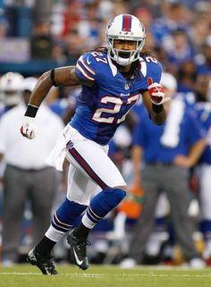 a football player running with the ball in his hand and people watching from the stands behind him