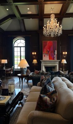 a living room filled with lots of furniture and a chandelier hanging from the ceiling