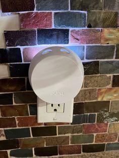 a white urinal mounted to the side of a brick wall