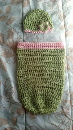 a crocheted green and pink diaper with a hat on it's head