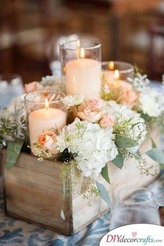 a wooden box filled with white and pink flowers on top of a blue table cloth