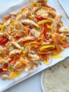 chicken fajita with peppers and onions on a tray next to a tortilla