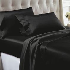 a bed with black sheets and pillows on it