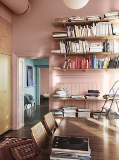 a dining room with pink walls and bookshelves