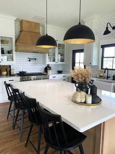 a large kitchen with white counter tops and black chairs in front of an island top