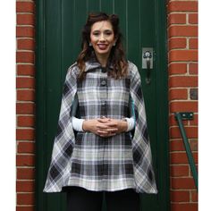 a woman standing in front of a green door wearing a black and white ponchy