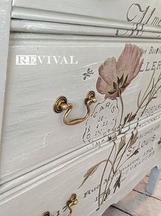 the drawers are painted white and gold with flowers on them, as well as lettering