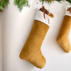 two christmas stockings hanging on a wall next to evergreen branches and other holiday decor items