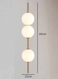 three white balls hanging from a brass colored light fixture with measurements for the length and width