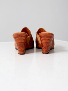 "This is a pair of 1950s vintage tooled leather wedges. The southwestern heels feature a tooled floral pattern. They have an inside elastic band for width. The slender open to sandals have a wedge heel. Brand: Campos CONDITION In good condition with wear consistent with age and use. Light usage wear to sole, insoles, and elastic band. Lovely patina to leather. MARKED SIZE: 8 FITS LIKE: 7.5 MEASUREMENTS Insole Length: 10\" .. 25.4 cm Width: 3.25\" .. 8.3 cm Height: 3\" .. 7.6 cm 91804" Vintage Stacked Heel Summer Heels, Western Style Round Toe Summer Mules, Summer Retro Brown Mules, Western Style Round Toe Mules For Summer, Western Style Summer Slip-on Mules, Western Style Slip-on Summer Mules, Western Style Round Toe Heels For Summer, Vintage Brown Mules For Summer, Vintage Sandals With Stacked Heel For Spring