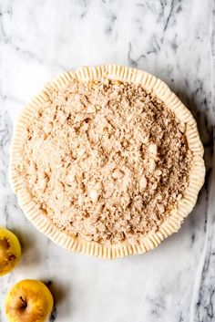 an uncooked pie sitting on top of a table next to two sliced apples