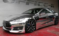 a silver and black car parked in front of a garage door on a red floor