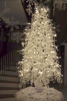 a white christmas tree with snowflakes on it in front of stairs and railings