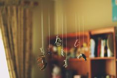 there are many toy animals hanging from the strings in this room with bookshelves