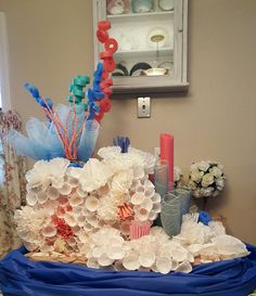 an arrangement of flowers and candles on a blue table cloth in a room with beige walls