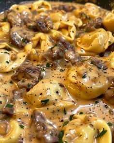 a skillet filled with pasta and meat covered in gravy