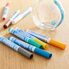 four pens are lined up on a table next to a glass vase and pen holder